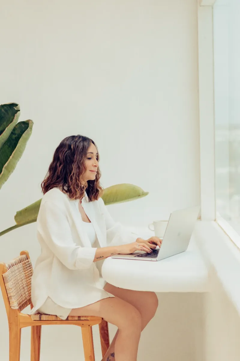 Ana Albiol trabajando en su laptop junto a una ventana con vista al mar
